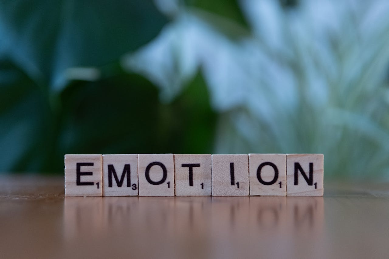 digital Wooden Scrabble tiles spelling 'Emotion' with a natural blurred background.